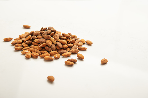 Pile of brown almonds nuts on white quartz counter top