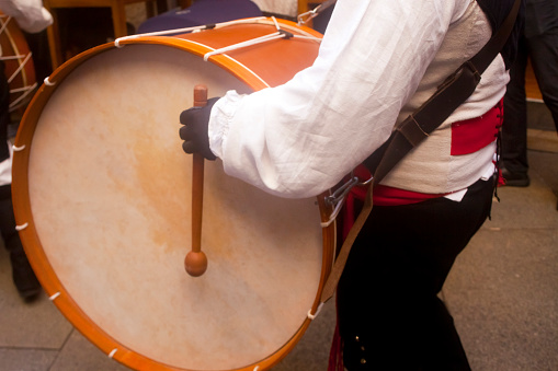 Lugo, Spain- October 10, 2021: Folk  musician wearing traditional clothing , playing drum in a narrow pedestrian  street during San Froilán annual celebrations, traditional festival in Lugo city Galicia, Spain.