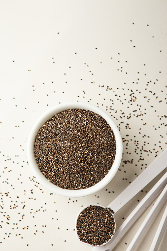 High angle view of Measuring spoon with a small white bowl of chia seeds on quartz counter top