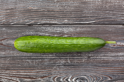 one cucumber on wood background