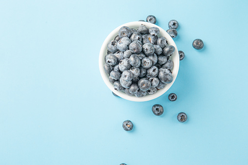 Fresh blueberries in a white bowl. Close up, top view. Copy space for text.
