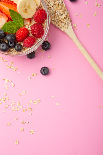 Oatmeal bowl with mixed berries on pink background.