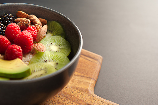 Healthy Oatmeal bowl on wooden cutting board on grey background.