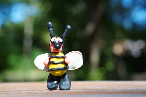 A figurine of a fabulous bee made of plasticine in close-up.