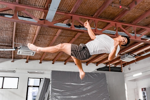 Asian Man Kick Flipping Acrobatic in Gym Studio