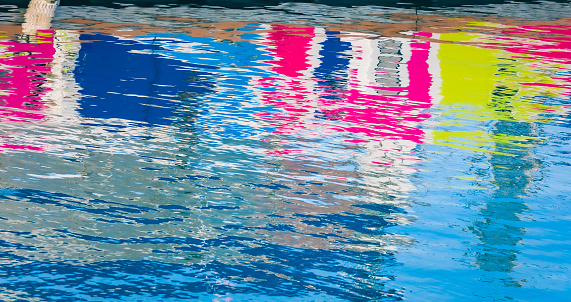 Abstract water reflection patterns from a colorful boat docked in the Royal Naval Dockyard in Bermuda