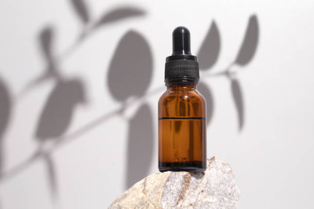 istock Cosmetic bottle serum, oil on stone stand with shadow branch eucalyptus on grey background. Natural cosmetics concept, skin care product. Beauty concept for face body care 1402291276