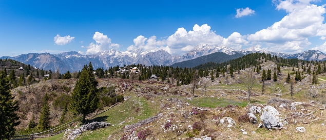 A picture of the landscape of Velika Planina, or Big Pasture Plateau, with the Kamnik-Savinja Alps on the background.