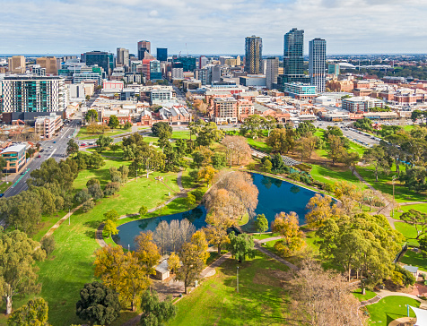 Vista aérea de pequeños edificios de la ciudad capital con un vibrante parque verde y un lago azul photo