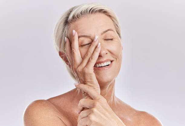 One happy mature caucasian woman relaxing with a hand on her face against a pink background. Smiling senior woman resting, caring for her skin while doing a skincare routine One happy mature caucasian woman relaxing with a hand on her face against a pink background. Smiling senior woman resting, caring for her skin while doing a skincare routine semi dress stock pictures, royalty-free photos & images