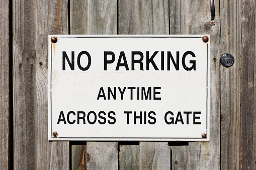 Metal No Parking sign on an old wooden gate.