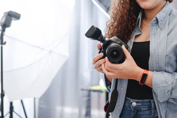 mulher fotógrafa desconhecida segurando uma câmera profissional no estúdio. - fotógrafo - fotografias e filmes do acervo