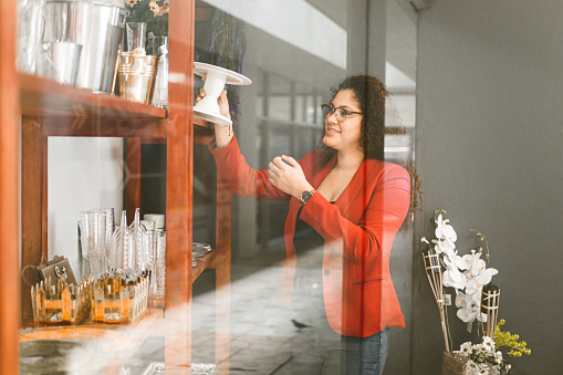 Latin american female entrepreneur holding a glass of item shelf