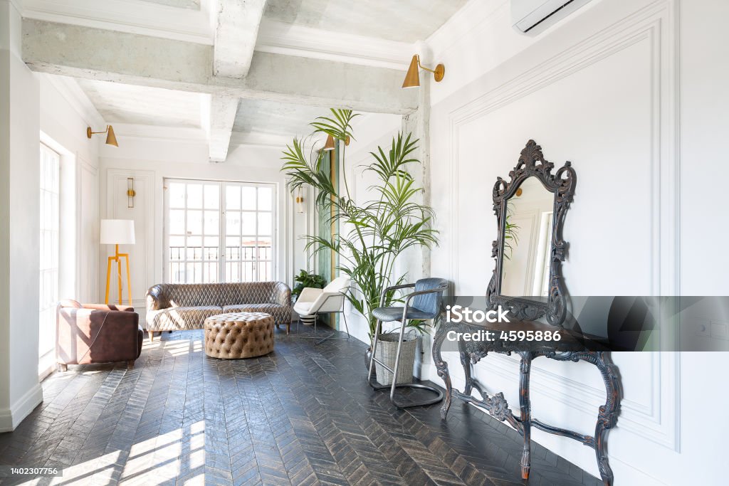 Chic, luxurious guest room design with old-fashioned antique furniture. white walls are decorated with relief. there is a beautiful dark brown parquet on the floor. Living Room Stock Photo