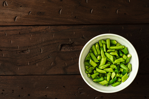 High angle view of chopped green beans in a salad bowl over a rustic wood table in the kitchen.Image made in studio.