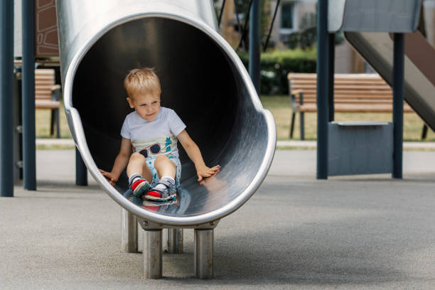 istock Happy child riding down slide on playground. 1402312809
