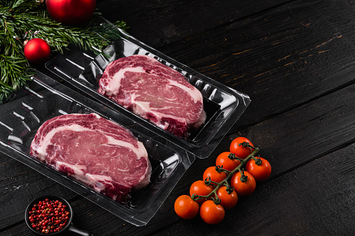 Meat in a package set, on black wooden table background, with copy space for text
