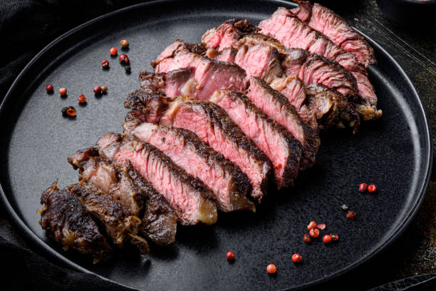 istock Sliced grilled rib eye beef steak beef marbled rare, on plate, on old dark rustic background 1402315880