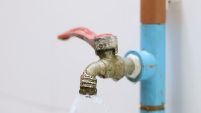 Slow motion shot of water leaking from faucet