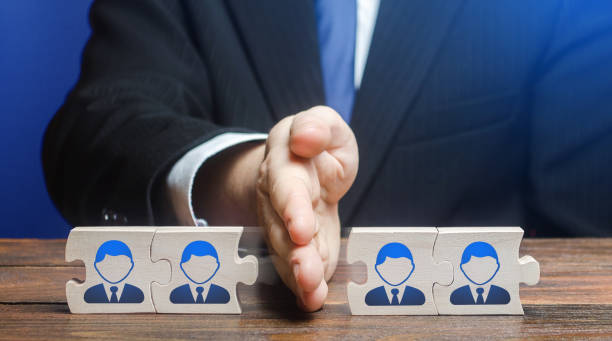 istock A man divides puzzle team of employees. Team split, structural fragmentation into small units. Improving company efficiency. Staff dismissal reduction. Distribution group members to parallel projects. 1402318400