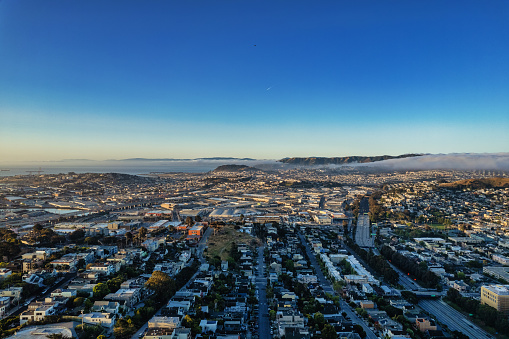 An aerial view of fog moving in over south San Francisco. The 101 and 280 freeways are visible in the morning light.