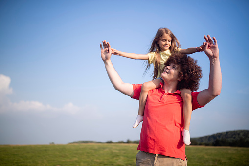 Uncle enjoys nature with his sweet niece he holds high on his shoulders.