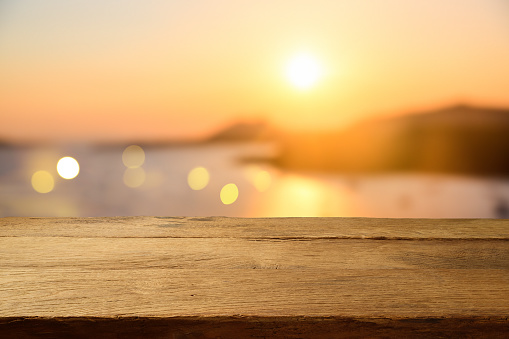 Empty wooden table over sunset blurred background. Summer vacation mock up design and product display