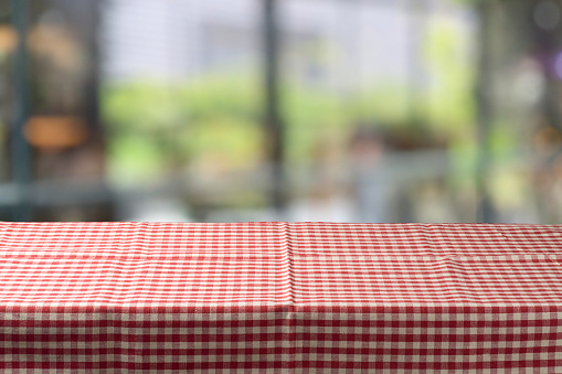 Red checked tablecloth on table over window blurred  background. Kitchen interior mock up for design and product display