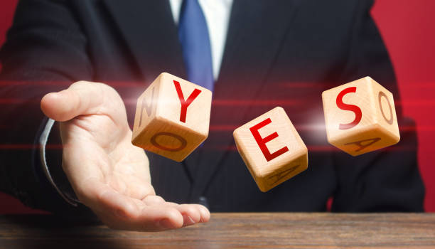 istock Cubes thrown by a man make up word YES. Agreement and acceptance, answer the question. Confirmation and approval. Important decision. Correct answer. Courage, irresistibility, zeal forwards, consent. 1402323692