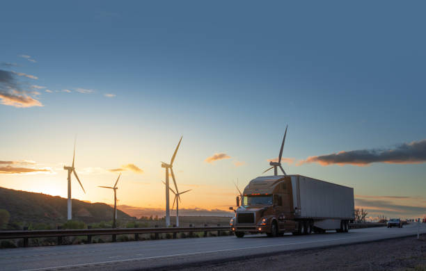 semirremolque a toda velocidad frente a turbinas eólicas en utah, ee. uu. - semi truck cargo container shipping truck fotografías e imágenes de stock