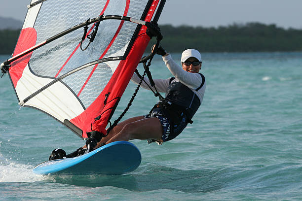 Windgirl A young woman sweeping over a blue lagoon on a windsurfer windsurfing stock pictures, royalty-free photos & images