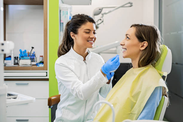 istock Young female dentist with patient examining teeth 1402328252