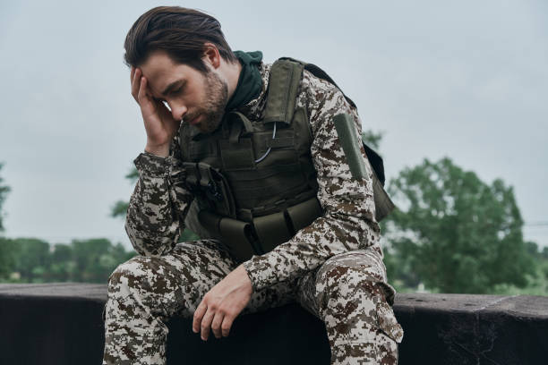 istock Tired young man in military uniform holding head in hand 1402328552