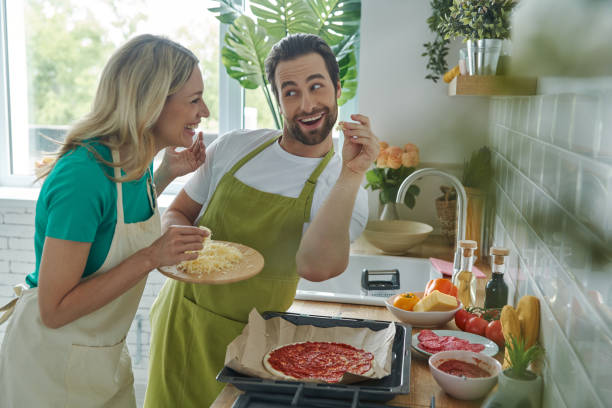 istock Cheerful couple sprinkling grated cheese on pizza 1402329584