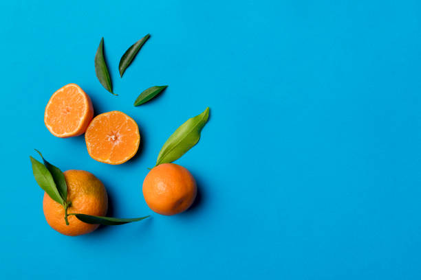 istock Many fresh ripe mandarin with green leaves on colored background, top view, space for text 1402330779