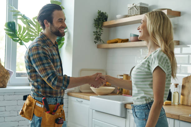 Beautiful young woman shaking hand to male plumber