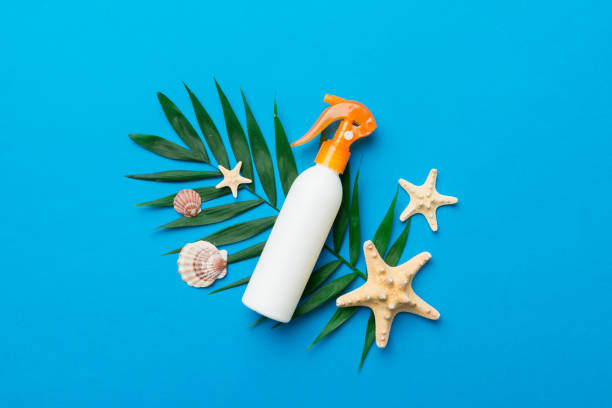 Sunscreen spray bottle. Bottle with sun protection cream and sea shells with tropical green leaf on color background, top view Sunscreen spray bottle. Bottle with sun protection cream and sea shells with tropical green leaf on color background, top view. shell starfish orange sea stock pictures, royalty-free photos & images