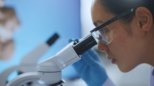 Medical Science Laboratory Scientist Looking at Sample under Microscope