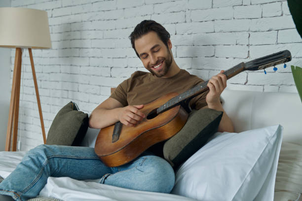 istock Handsome young man playing acoustic guitar and smiling 1402332221