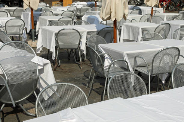 istock empty chairs and tables with white tablecloth without customers in the alfresco restaurante in the square of European city 1402332246