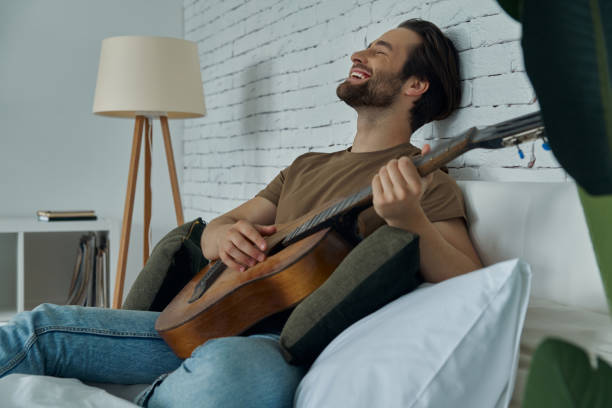 istock Happy young man playing acoustic guitar 1402332944