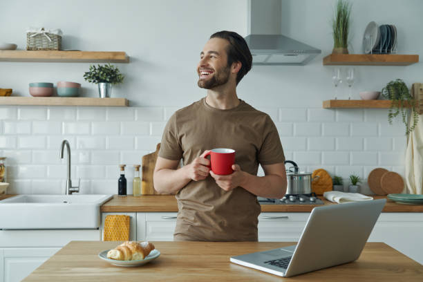 istock Cheerful young man enjoying coffee and looking away 1402334241