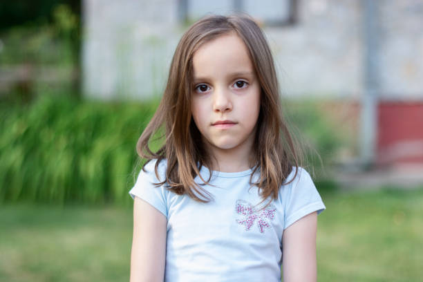 Portrait of a serious girl looking at camera Portrait of a serious girl looking at camera in the yard brown hair brown eyes girl stock pictures, royalty-free photos & images