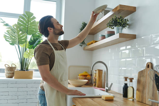 istock Good looking young man placing dishes on shelf 1402334304