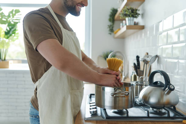 istock Close-up of young man placing spaghetti into the pan 1402334490