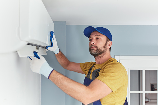 Repairman cleaning and fixing indoors AC unit.