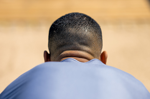 African American man neck, shoulders and back of head close up. Young guy in sport T-shirt backside view