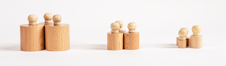 Hierarchy, ranking, teamwork concept. Row of Montessori knobbed cylinders placed in groups depending on diameter and height. Wooden childish game. High quality photo