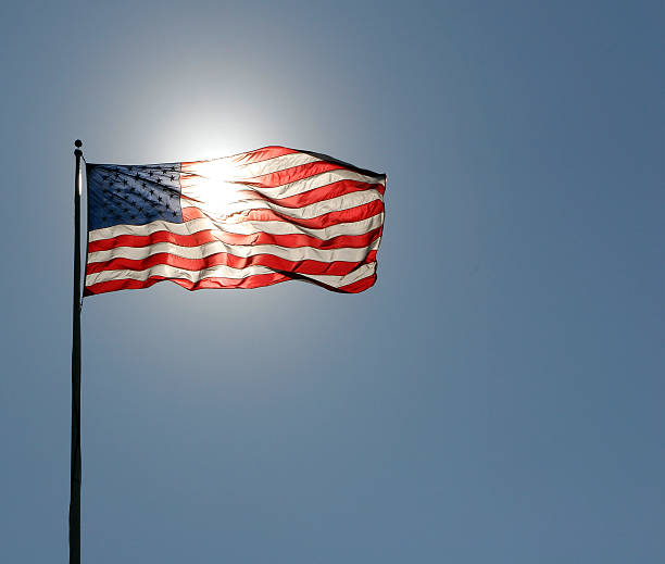 american flag with sun behind stock photo