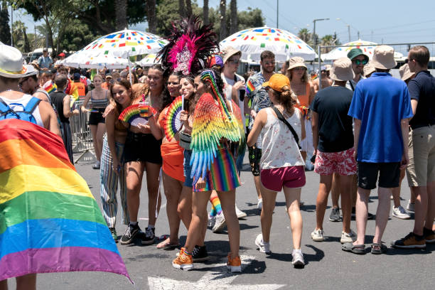 Happy smiling girls with lgbt flags and other lgbt attributes posing on the gay pride parade stock photo